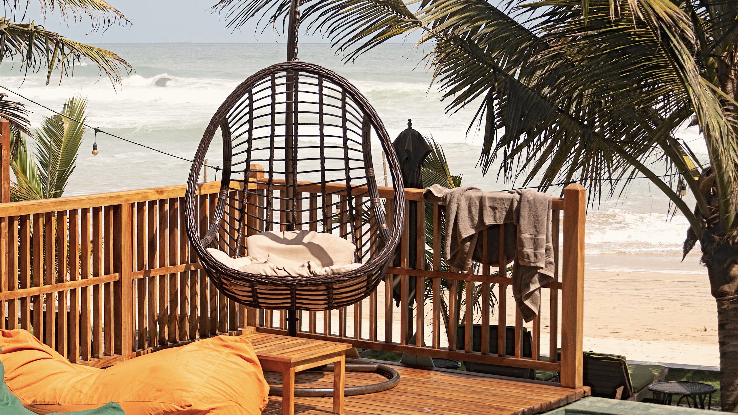Hanging rattan chair and beanbags on the timber deck above the beach