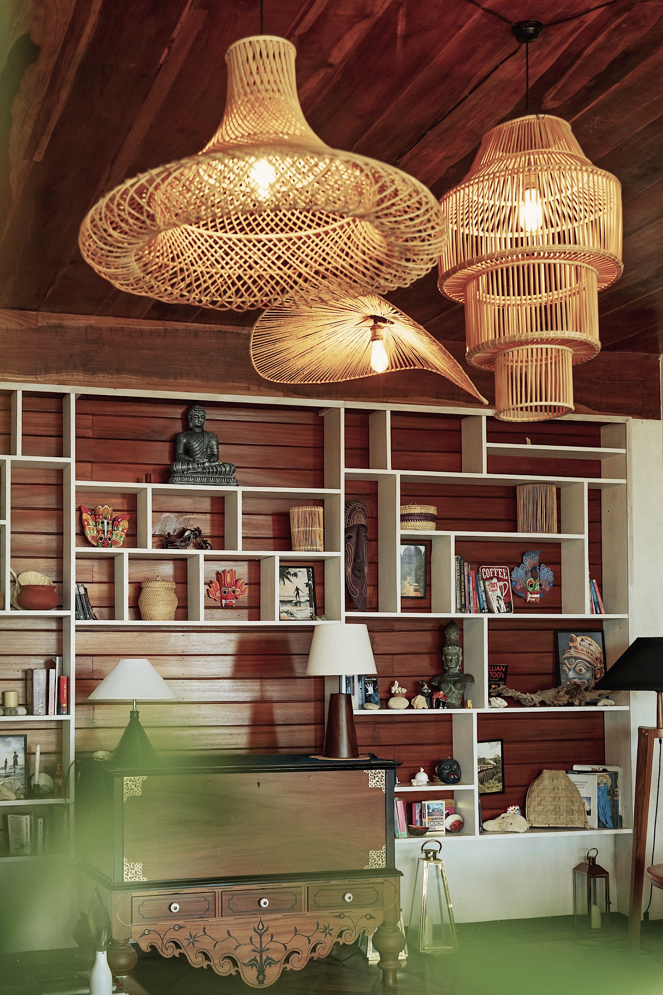 Rattan pendant lights above shelves of books and keepsakes